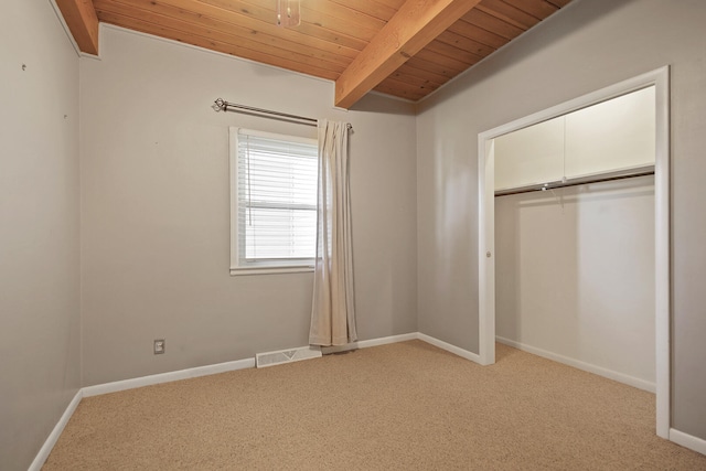 unfurnished bedroom with light carpet, beam ceiling, a closet, and wood ceiling