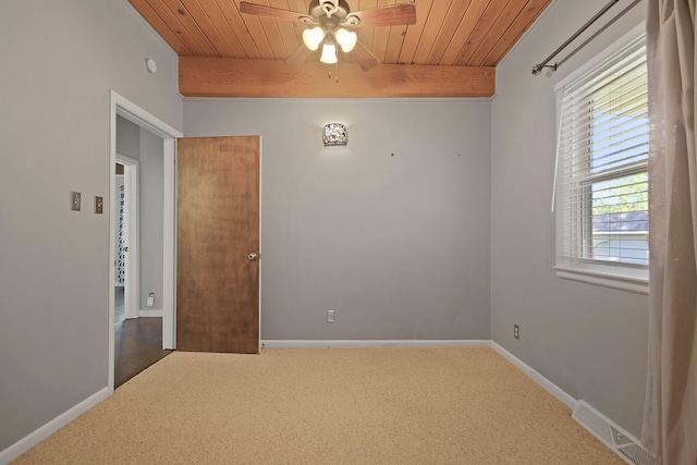 carpeted spare room with beamed ceiling, ceiling fan, and wooden ceiling