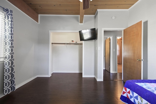 unfurnished bedroom with ceiling fan, beamed ceiling, wood ceiling, a closet, and dark hardwood / wood-style floors