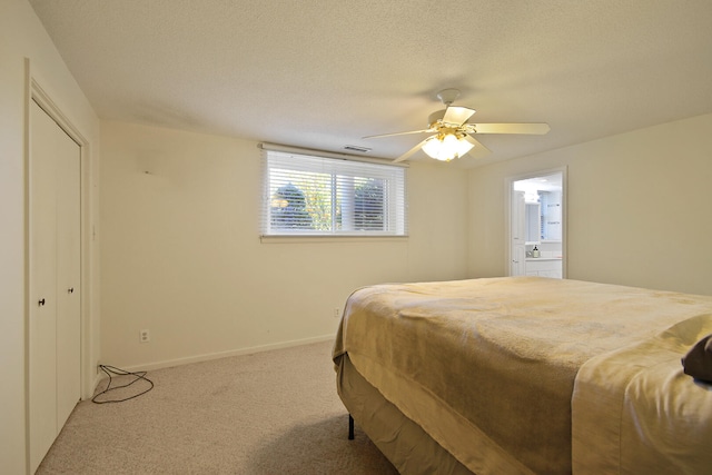 bedroom with ceiling fan, a textured ceiling, light carpet, and ensuite bath