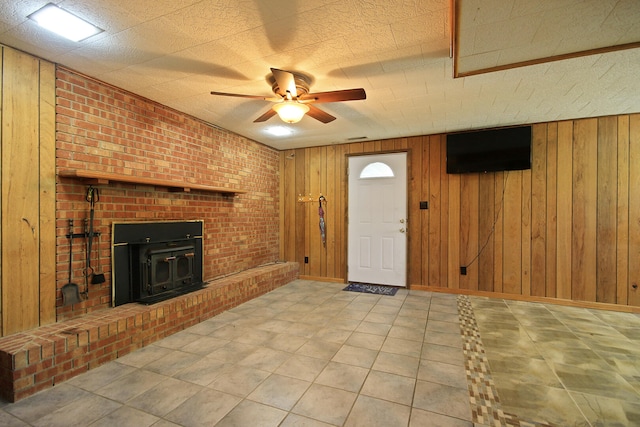 foyer with ceiling fan, wooden walls, and brick wall