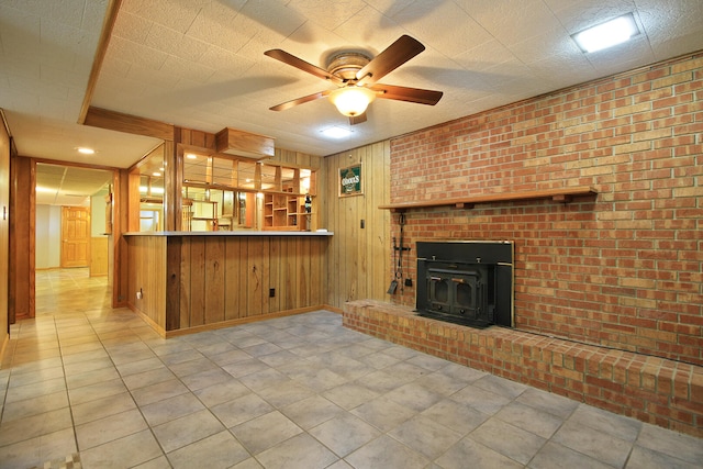 unfurnished living room with wood walls, light tile patterned flooring, a fireplace, and ceiling fan