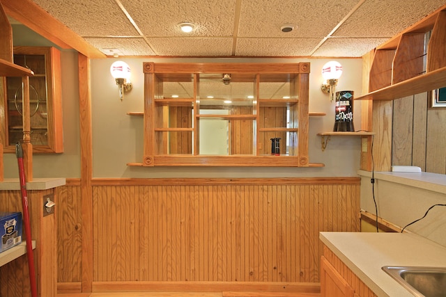 interior space featuring wood walls, a drop ceiling, and sink