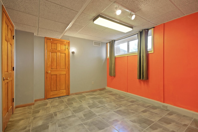 spare room with a paneled ceiling and track lighting