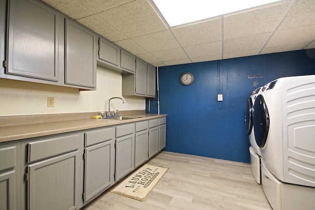 laundry area featuring cabinets, light hardwood / wood-style flooring, sink, and washing machine and dryer