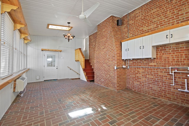 kitchen featuring wood walls, a chandelier, white cabinets, high vaulted ceiling, and a wall mounted AC