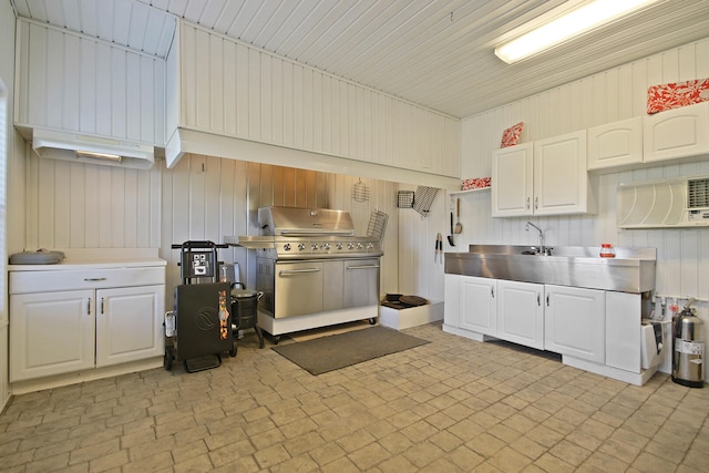 kitchen with stainless steel counters, white cabinets, and wooden walls