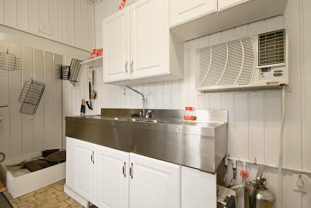 kitchen featuring stainless steel counters, white cabinets, and an AC wall unit