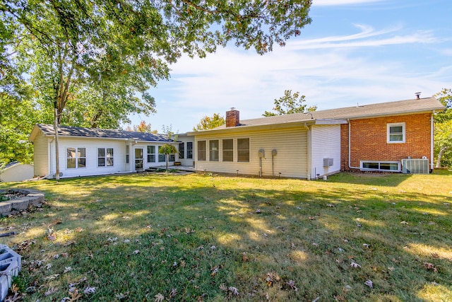 back of house with cooling unit and a lawn