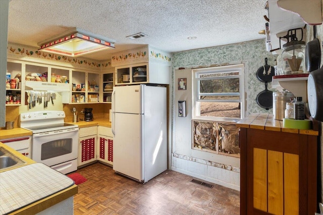 kitchen with a textured ceiling, dark parquet flooring, sink, and white appliances