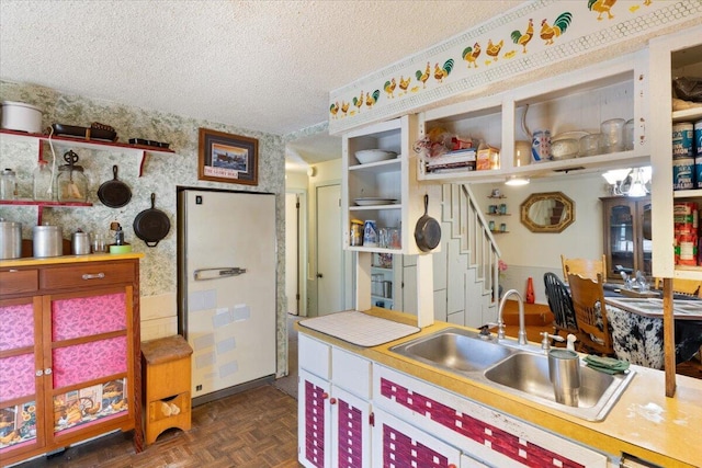 kitchen with dark parquet flooring, sink, a textured ceiling, and white refrigerator