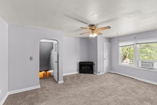 unfurnished living room with ceiling fan, cooling unit, a wood stove, and carpet