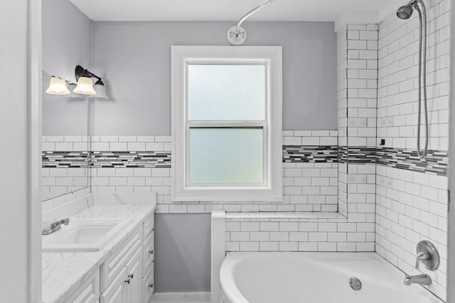 bathroom with plenty of natural light, tile walls, vanity, and tiled shower / bath