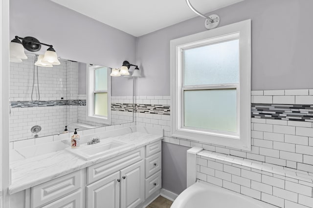 bathroom with tiled shower / bath combo, vanity, and tile walls