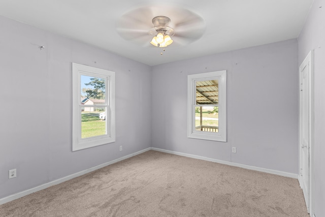 spare room featuring a healthy amount of sunlight, ceiling fan, and light colored carpet