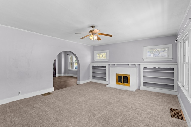 unfurnished living room with ornamental molding, carpet flooring, and ceiling fan