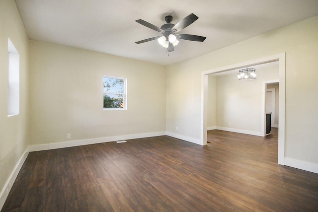 spare room featuring ceiling fan with notable chandelier and dark hardwood / wood-style flooring