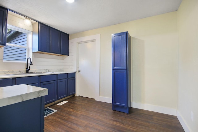 kitchen with blue cabinets, a textured ceiling, dark hardwood / wood-style floors, and sink