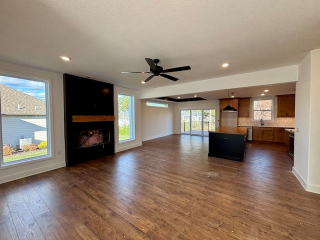 unfurnished living room featuring a large fireplace, baseboards, dark wood finished floors, and recessed lighting