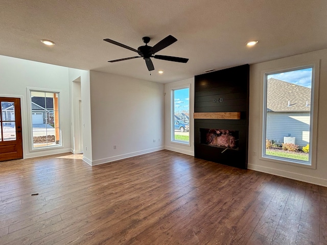 unfurnished living room with baseboards, a fireplace, wood finished floors, and a healthy amount of sunlight