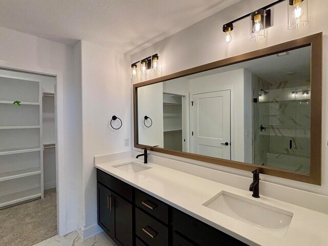 bathroom featuring a walk in closet, a sink, and a marble finish shower