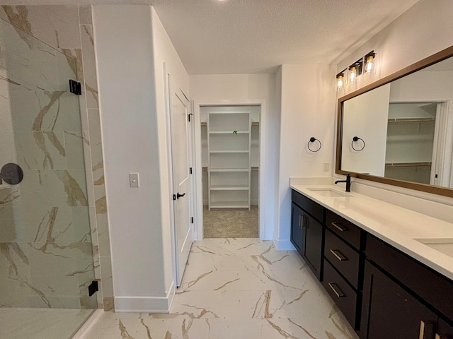 full bath with marble finish floor, a spacious closet, a marble finish shower, and a sink