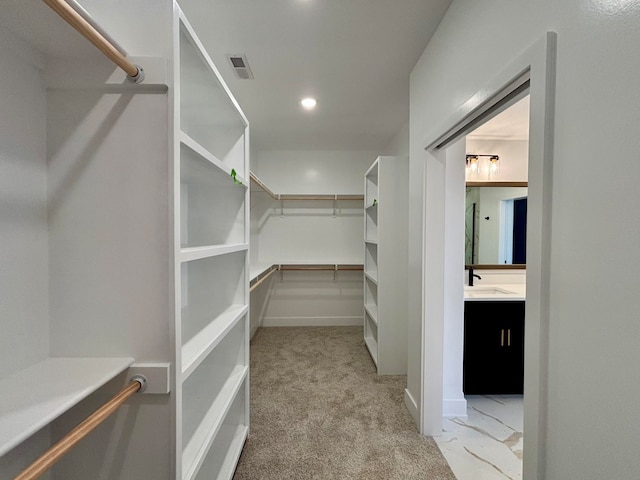 walk in closet with a sink, visible vents, and light colored carpet