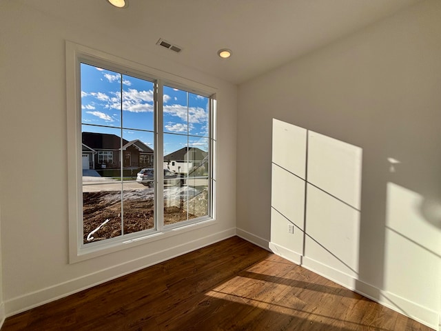 spare room with baseboards, visible vents, dark wood-style floors, a residential view, and recessed lighting