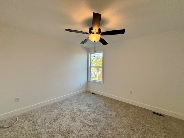 empty room featuring a ceiling fan, visible vents, light carpet, and baseboards