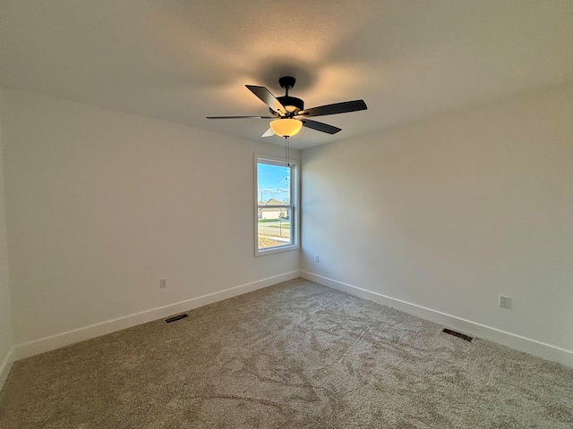 spare room with a ceiling fan, carpet, visible vents, and baseboards