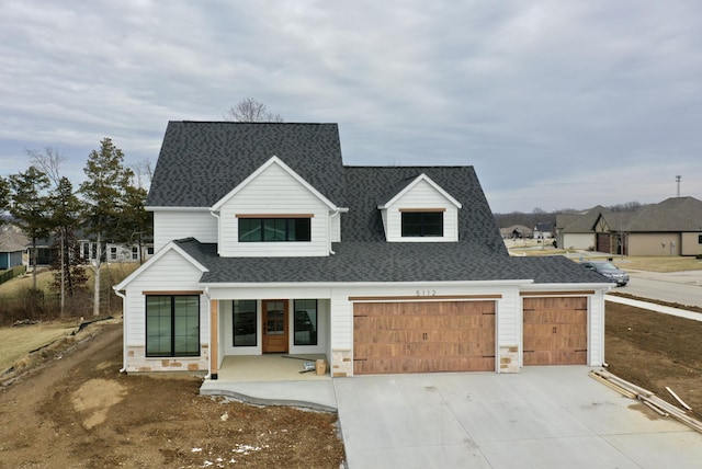 modern inspired farmhouse featuring a garage, stone siding, driveway, and roof with shingles