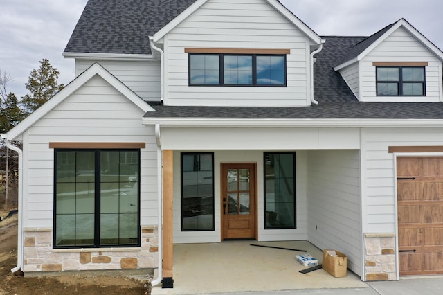 exterior space with stone siding and a shingled roof