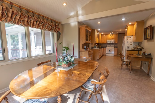 tiled dining space with lofted ceiling and sink