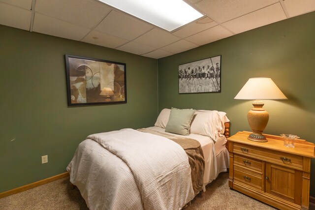 bedroom with a drop ceiling and light carpet