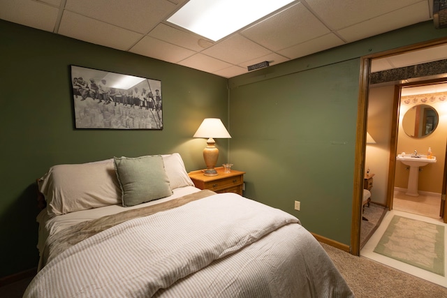 carpeted bedroom featuring ensuite bath and a paneled ceiling