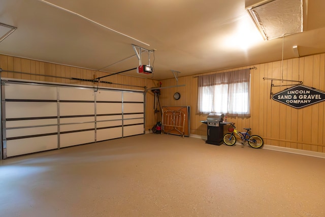 garage featuring a garage door opener and wooden walls