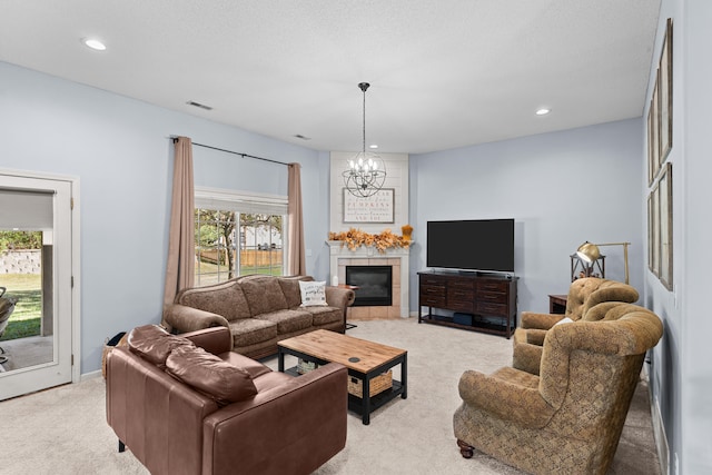 carpeted living room with a tiled fireplace, a notable chandelier, a healthy amount of sunlight, and a textured ceiling