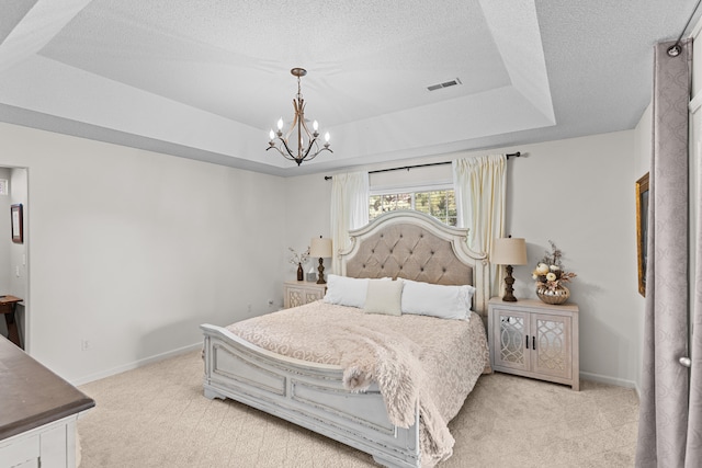 bedroom with a chandelier, light colored carpet, a textured ceiling, and a raised ceiling