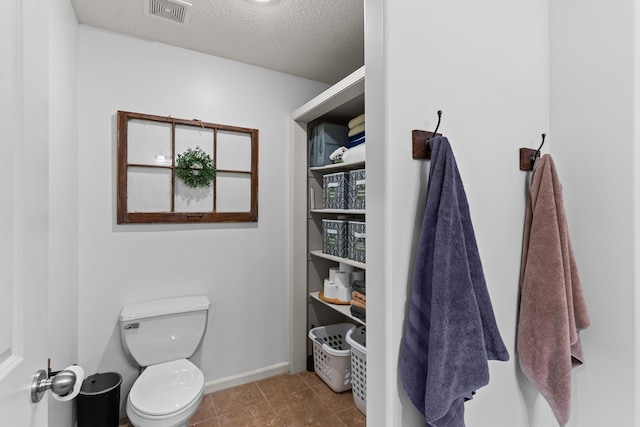 bathroom with toilet, a textured ceiling, and tile patterned floors