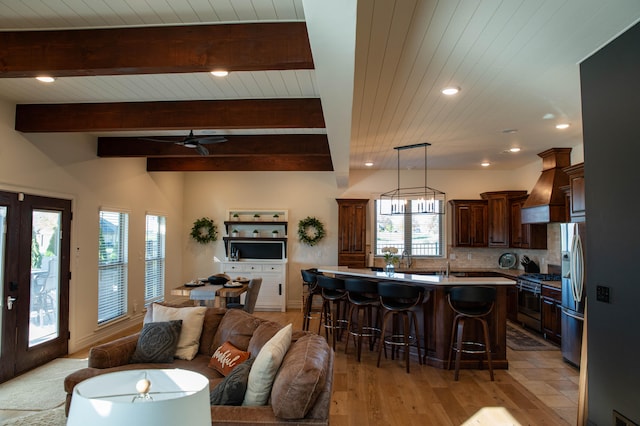 kitchen with decorative backsplash, light hardwood / wood-style flooring, a center island with sink, a kitchen bar, and appliances with stainless steel finishes