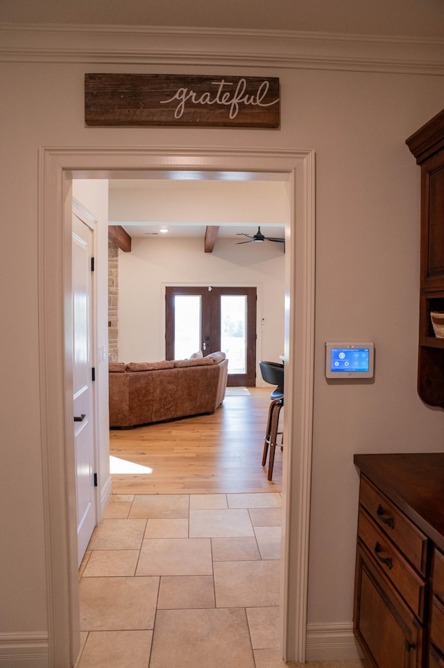 corridor with light hardwood / wood-style floors, french doors, ornamental molding, and beam ceiling