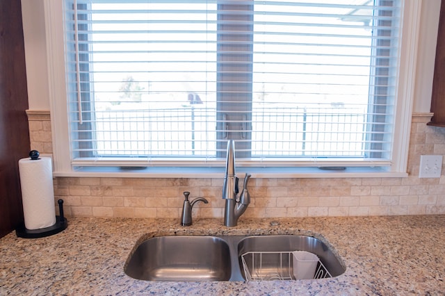 details with tasteful backsplash, sink, and light stone countertops