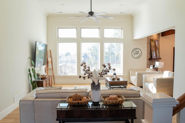 living room featuring light hardwood / wood-style floors, ornamental molding, and ceiling fan