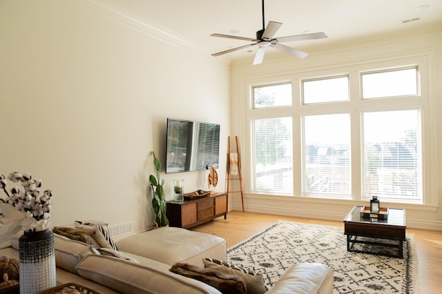 living room with ornamental molding, light wood-type flooring, and ceiling fan