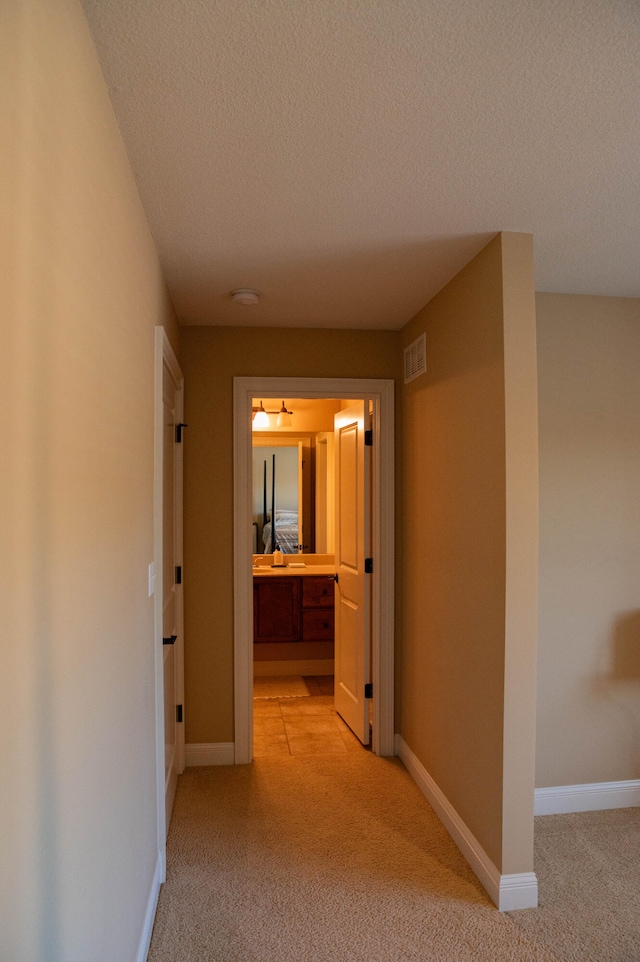 hall with light carpet and a textured ceiling