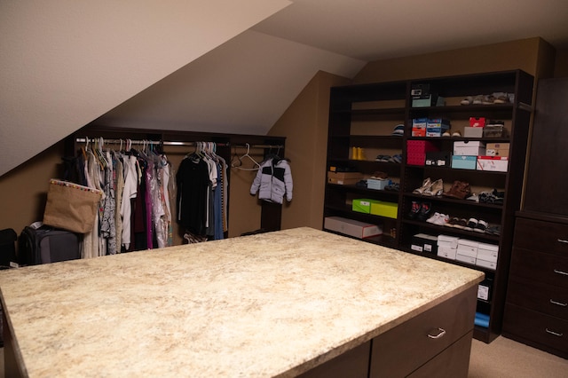 walk in closet with lofted ceiling and light colored carpet