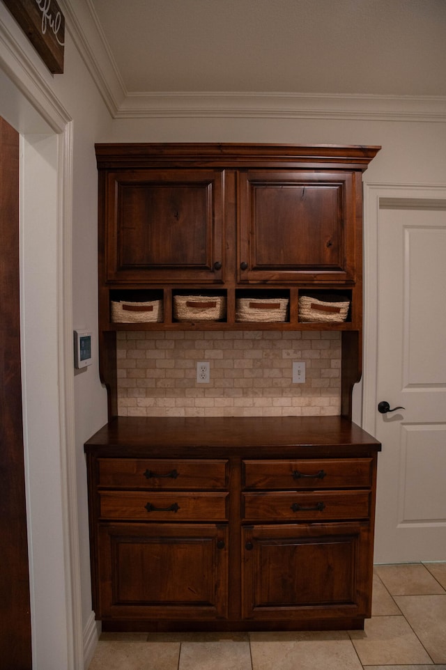 interior space with ornamental molding, dark brown cabinetry, light tile patterned floors, and tasteful backsplash