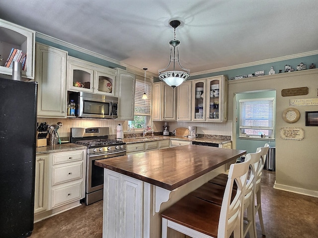 kitchen with butcher block counters, stainless steel appliances, a center island, and a wealth of natural light