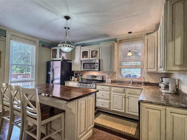 kitchen featuring sink, a center island, stainless steel appliances, decorative light fixtures, and ornamental molding