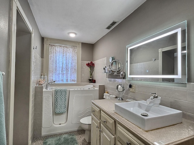 full bathroom with toilet, vanity, tile patterned floors, and tile walls